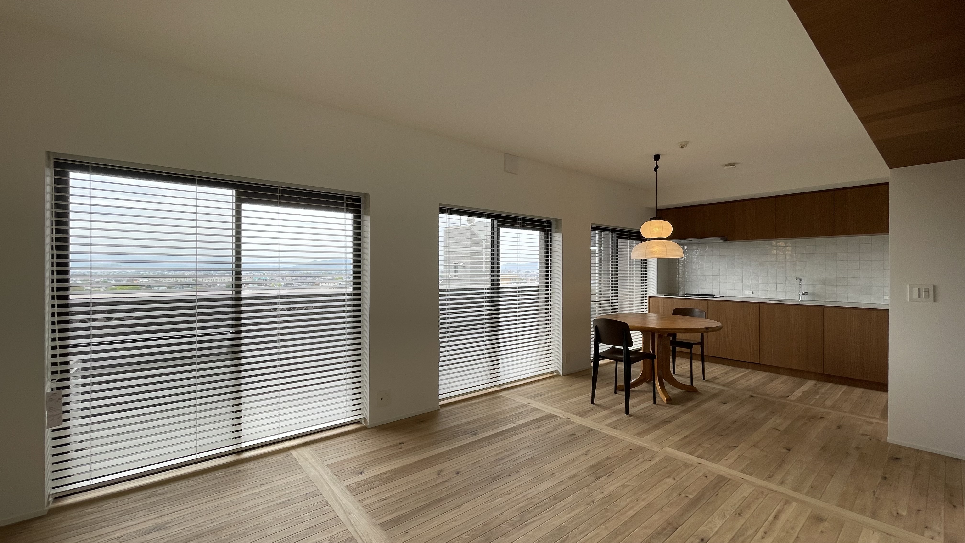 View of the living room. &Tradition light , Jean Prouvé Chair and Daumiller Table. Natural light from the window. Wood floor korean style and brand new kitchen with a retro style.