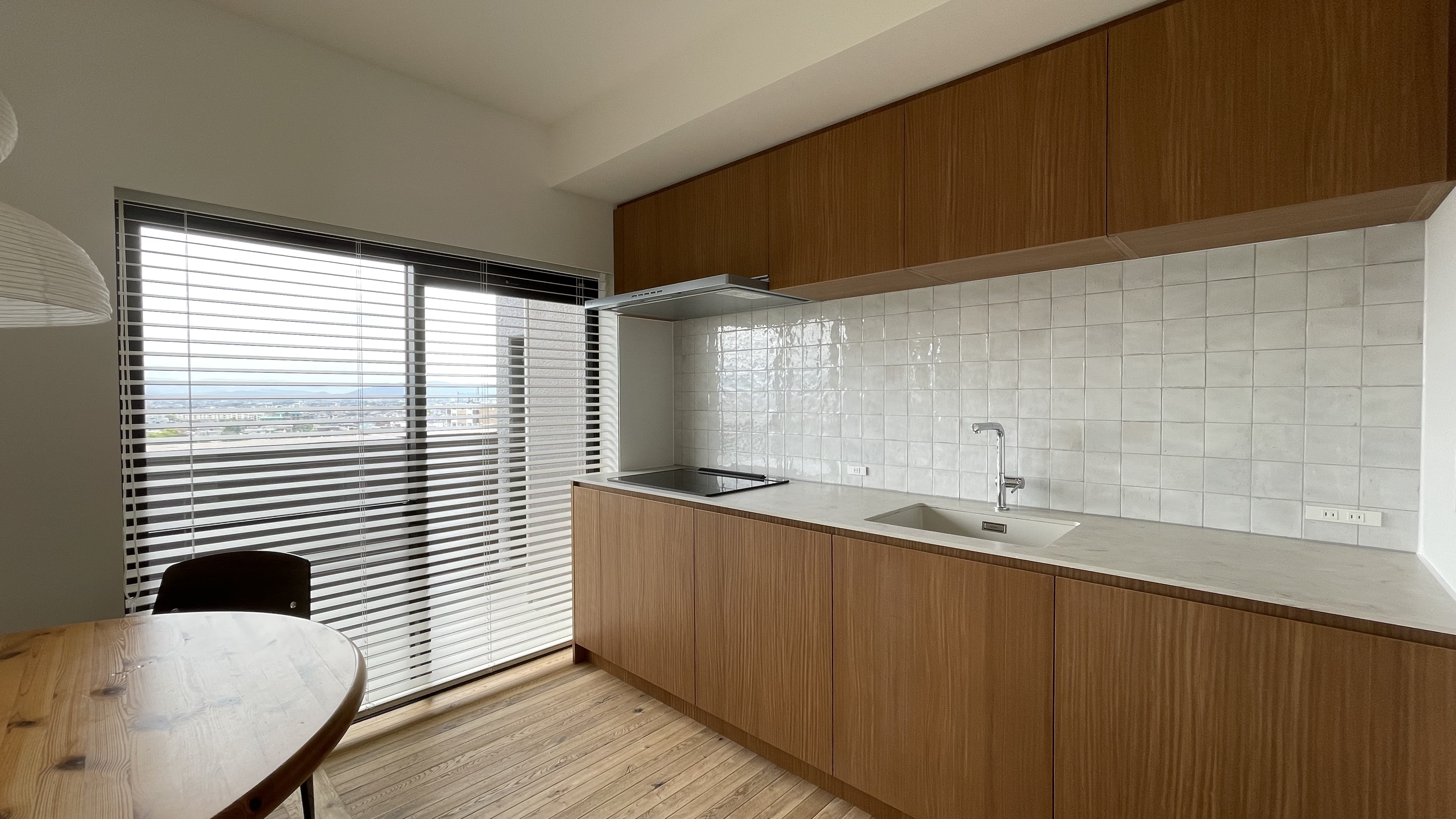 View of the kitchen, with wood plate for the furnitures Use of vintage style white ceramic wall tiles, &Tradition light , Jean Prouvé Chair and Daumiller Table. Natural light from the window. Wood floor korean style