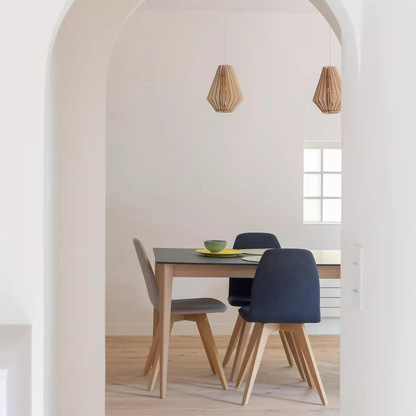 A renovated living room with wooden flooring and modern decorative elements in a grey, European-inspired style. The furniture and lighting are designed by French and American designers.