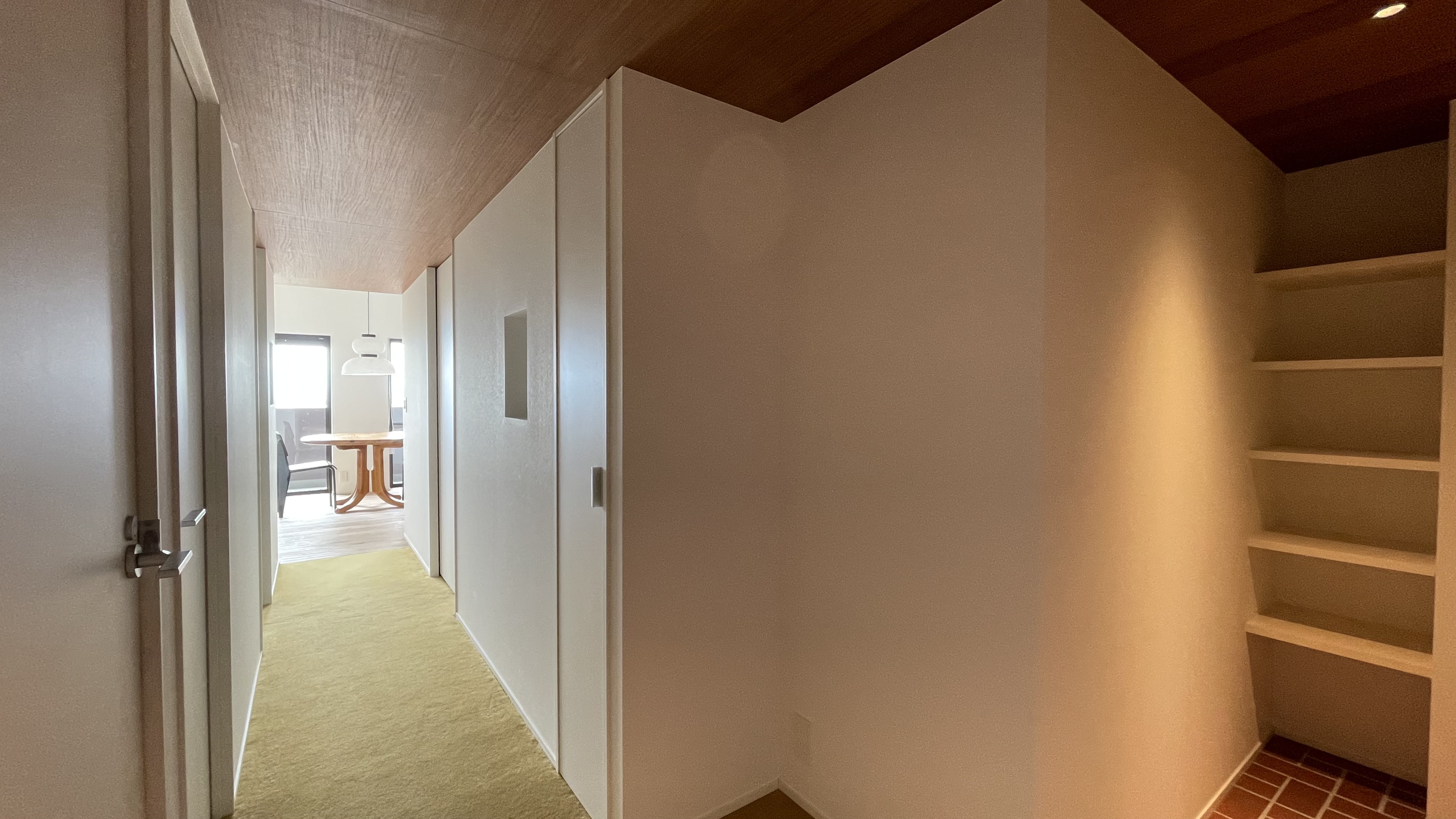 Next to entrance, view of the corridor and the shoes space. Brick flooring style for the entrance and spot lights.