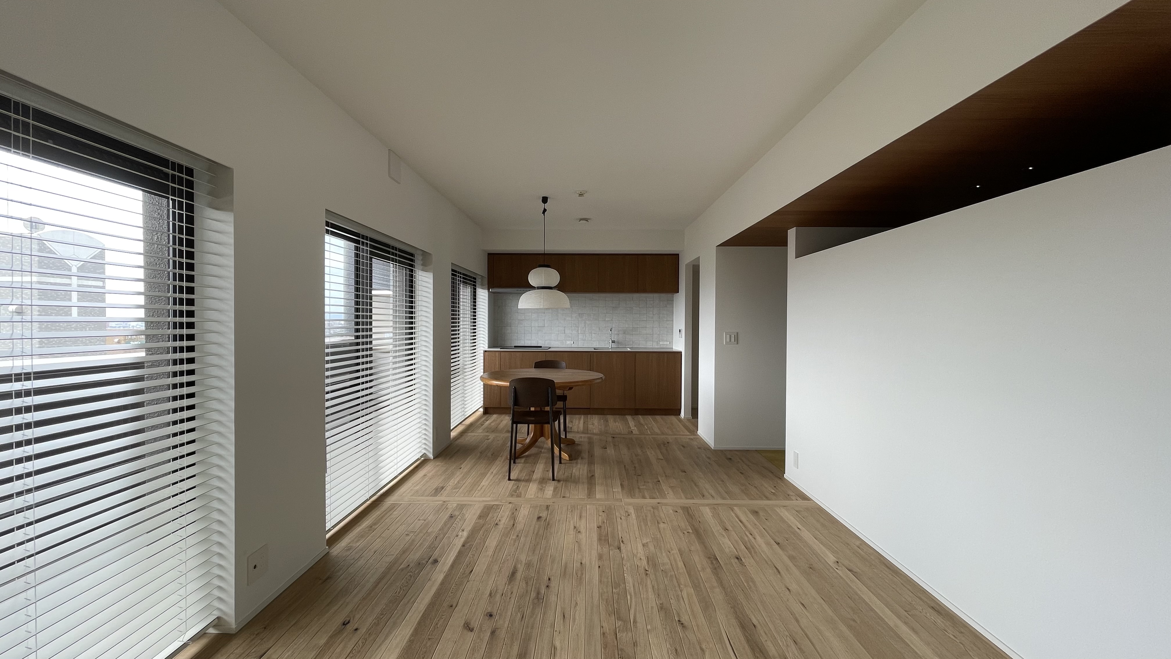 Back view of the living room. &Tradition light , Jean Prouvé Chair and Daumiller Table. Natural light from the window. Wood floor korean style and brand new kitchen with a retro style.